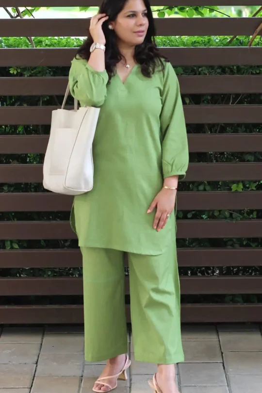 Woman wearing a sage green cotton slub tunic and wide-leg trousers set with a white tote bag. 👜