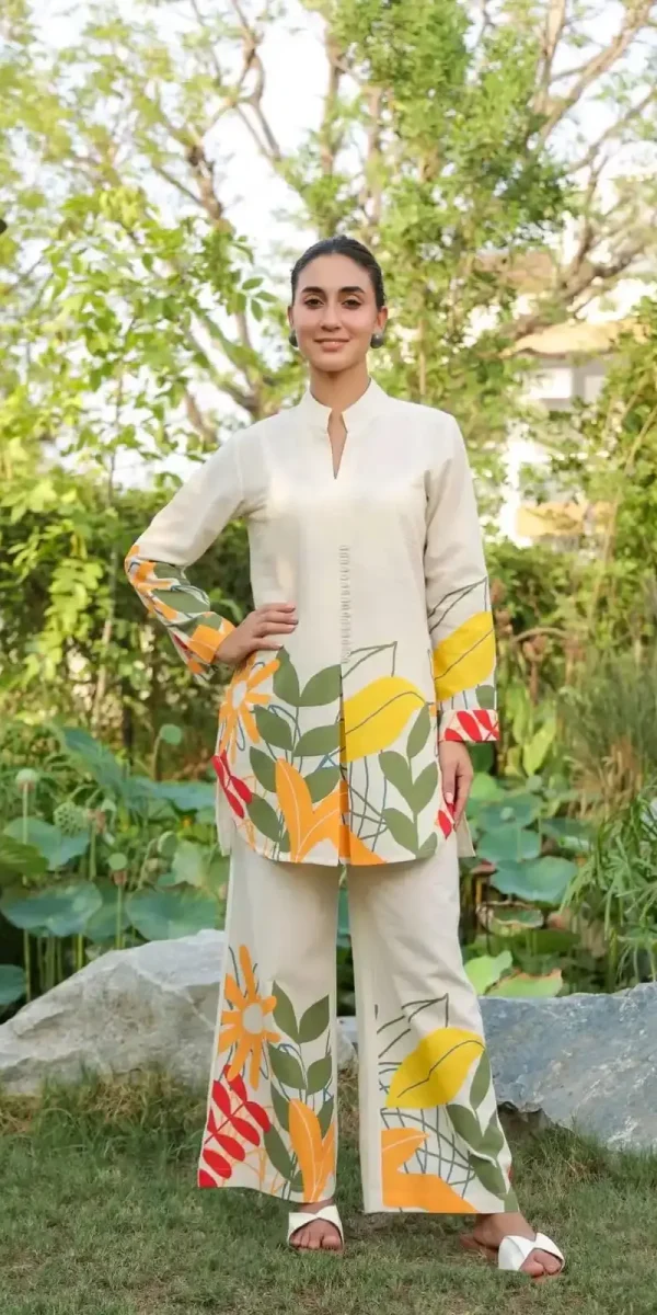 Woman wearing a cream-colored cotton flex co-ord set with vibrant yellow, orange, and green tropical leaf prints on the hem and sleeves.
